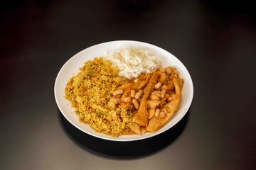 A classic Brazilian dish known as dobradinha, prepared with beef tripe, white beans, and tropical spices, served with traditional farofa made with toasted cassava flour.