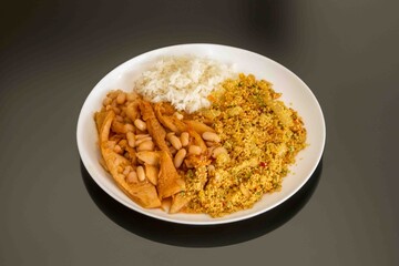 A classic Brazilian dish known as dobradinha, prepared with beef tripe, white beans, and tropical spices, served with traditional farofa made with toasted cassava flour.