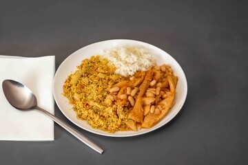 A classic Brazilian dish known as dobradinha, prepared with beef tripe, white beans, and tropical spices, served with traditional farofa made with toasted cassava flour.