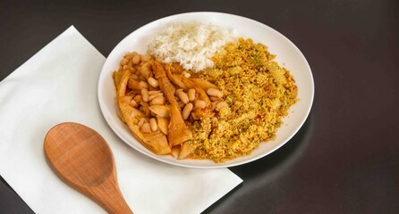 A classic Brazilian dish known as dobradinha, prepared with beef tripe, white beans, and tropical spices, served with traditional farofa made with toasted cassava flour.