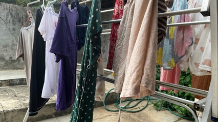 Clothes Drying on Rack Outdoors in Sunlight. Freshly washed clothes hanging on a drying rack outdoors under natural sunlight. Concept of eco-friendly laundry, air drying, and sustainable living.