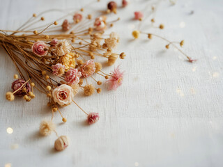 A bundle of dried wildflowers and seeds scattered on light fabric, warm indoor light and selective focus, rustic still life for decor projects.