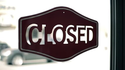 Owner placing a red closed sign on the glass door of a retail business store