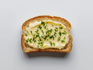 Slice of crusty bread topped with creamy butter and chopped herbs on parchment, overhead natural light, food styling ideal for recipe or menu use.