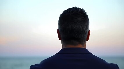 Businessman looking at the ocean flexing his biceps showing confidence
