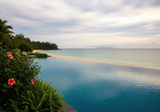 Serene tropical infinity pool reflecting the ocean and sandy beach under a cloudy sky.