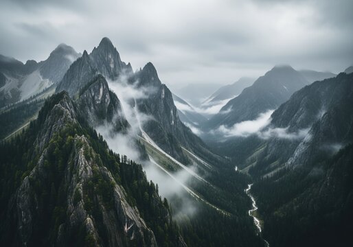 Moody cinematic aerial view of rugged mountain peaks shrouded in swirling mist and fog