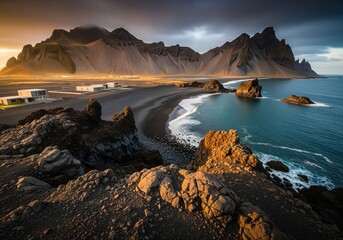 Obraz premium Majestic volcanic coastline landscape with black sand beach and rugged mountains at golden hour.