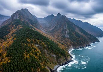 Dramatic aerial view of rugged mountain range coastline with autumn forest and cloudy sky