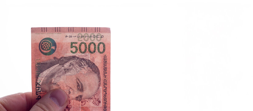 Horizontal banner. Male hand with 5000 dram banknote with portrait of writer William Saroyan on white. Photo of cash money of Armenia. Copy space. Concept of salary, bribe, tax, loan, debt, pay, bribe