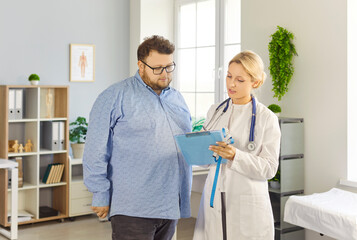 Patient and doctor consultation in medical clinic. Overweight fat man listens as female physician...