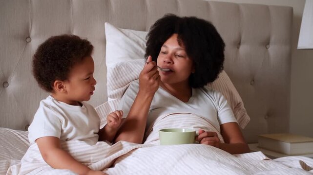 A tender moment as a mother feeds her child in bed, the love and care evident in their interactions Stock Video