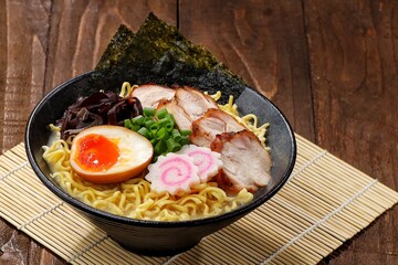 a Tonkotsu ramen bowl of traditional Japanese ramen with slices of chicken, halved boiled egg, seaweed, green onions, and other toppings