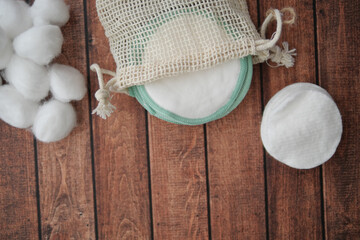Cotton pads and balls in natural fabric bag on wooden table