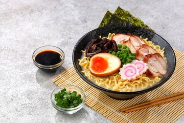 a Tonkotsu ramen bowl of traditional Japanese ramen with slices of chicken, halved boiled egg, seaweed, green onions, and other toppings