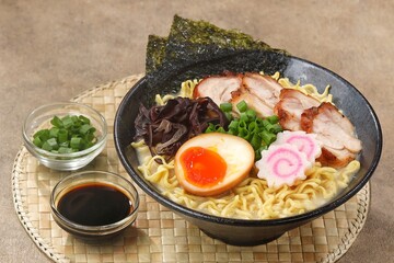 a Tonkotsu ramen bowl of traditional Japanese ramen with slices of chicken, halved boiled egg, seaweed, green onions, and other toppings