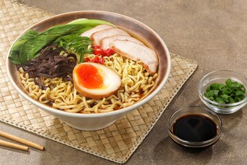 Ramen. Spicy noodle soup with egg, grilled chicken, seaweed and bok choy in a bowl