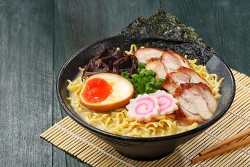 a Tonkotsu ramen bowl of traditional Japanese ramen with slices of chicken, halved boiled egg, seaweed, green onions, and other toppings