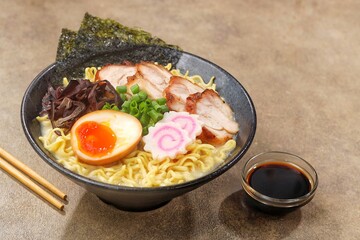 a Tonkotsu ramen bowl of traditional Japanese ramen with slices of chicken, halved boiled egg, seaweed, green onions, and other toppings