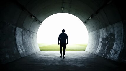 Sports athlete silhouette walking from dark tunnel into bright stadium light