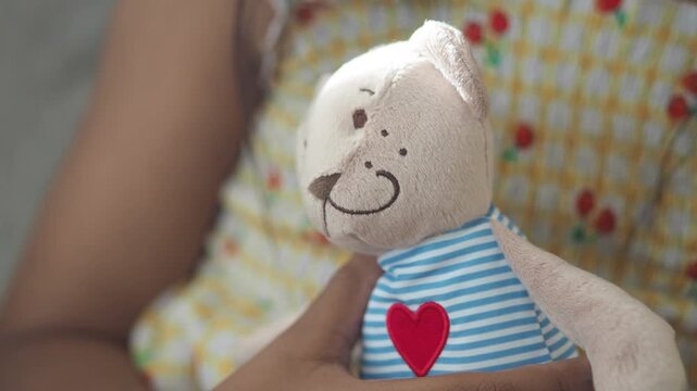 Child hugs a soft teddy bear with a heart patch