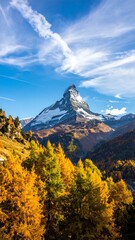 A tall, snow-capped peak rises in front of a blue sky with streaky clouds. Golden trees fill the foreground