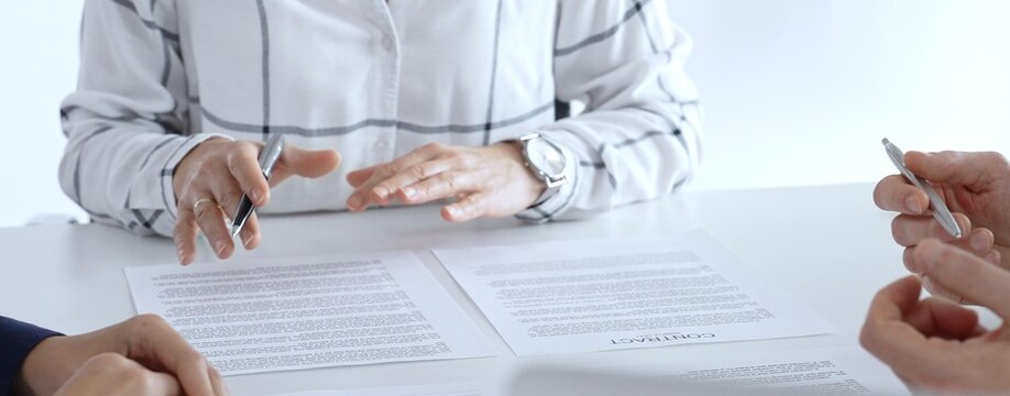 Business professionals or lawyers sitting at the desk in a bright office, reviewing and discussing contract papers. Teamwork concept - Powered by Adobe