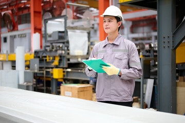 Engineer or technician writing on clipboard and checking metal sheet in the factory