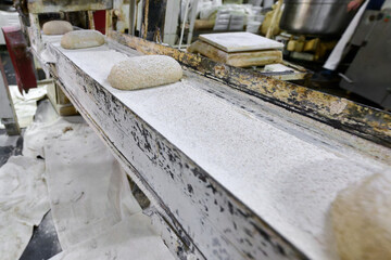 Dough moving on conveyor belt in a bakery during preparation for baking in a commercial kitchen environment