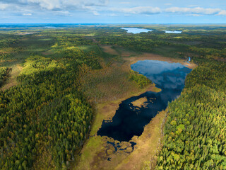 Fototapeta premium Scenic aerial view of a tranquil forest landscape with lakes and diverse greenery during a sunny day