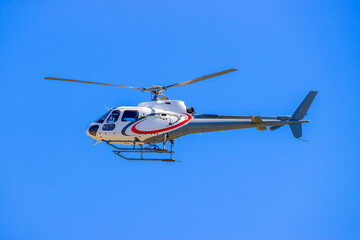 Photograph of a tourist sightseeing helicopter flying around a sporting event in regional Australia.