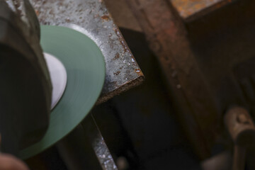 Focused shoemaker at workshop using grinding machine for shoe repair. This leather craft, handmade process, shows detailed work of traditional cobbler