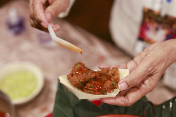 Person hand carefully serving delicious fried chicken food with tasty sauce. close up on meal preparation for perfect appetizer or snack with great tasting experience