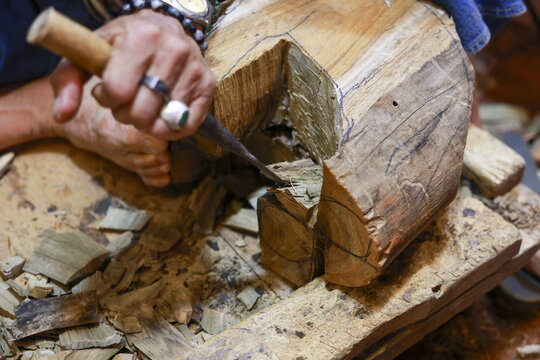 Focused craftsman carving wood with chisel in workshop. artisan hand shows great skill, dedicated carpenter making handmade sculpture with intense concentration