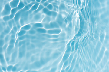 Blue water with ripples on the surface. Defocus blurred transparent blue colored clear calm water surface texture with splashes and bubbles. Water waves with shining pattern texture background.