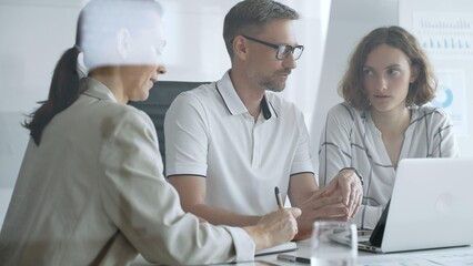 Professional team working together, reviewing digital analytics on laptop screen while strategizing corporate project details in modern workplace environment. Business people concept