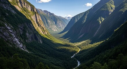 Obraz premium Aerial view of a lush green valley with a river winding through it, surrounded by towering mountains.