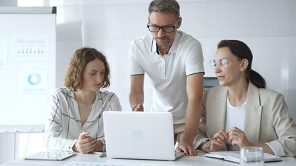 Business team collaborating and analyzing data on a laptop during a productive meeting in a modern office, fostering teamwork and strategic decision making