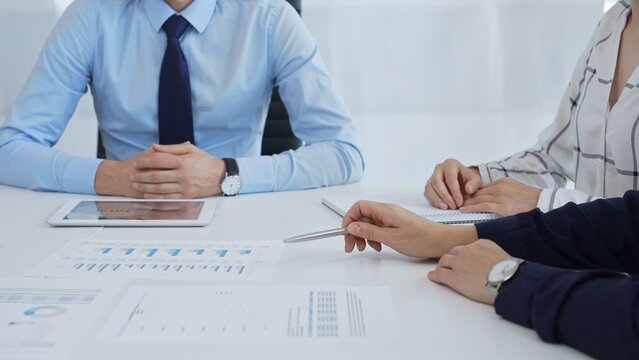 Business professionals discussing financial charts on tablet, collaborating closely while reviewing project data in modern corporate workspace