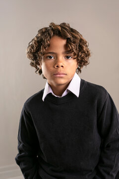 Cute fashion portrait of a diverse African American boy. Posed studio image of a handsome child wearing a collared shirt and a sweater