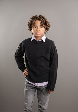 Cute fashion portrait of a diverse African American boy. Posed studio image of a handsome child wearing a collared shirt and a sweater