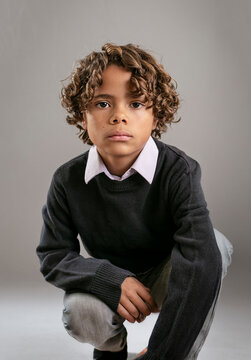 Cute fashion portrait of a diverse African American boy. Posed studio image of a handsome child wearing a collared shirt and a sweater
