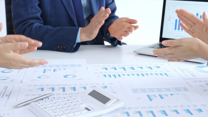 Business team clapping hands, celebrating financial success and achievement after a successful company presentation showing charts and data on a laptop screen