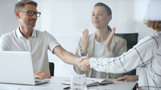 Business people are shaking hands after successful negotiation, colleagues clapping, celebrating agreement in modern office headset. Handshake concept