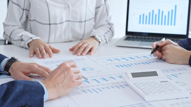 Business professionals analyzing financial data and market trends during a corporate meeting, collaborating on reports and planning strategic growth in the office