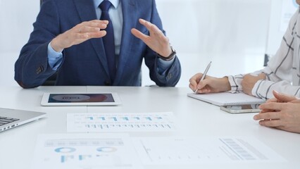 Business team collaborating in an office, analyzing financial data through digital tablets and documents during a meeting. Close up view of hands engaged in discussion and strategy planning