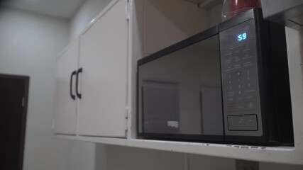 Person setting timer on a modern microwave oven