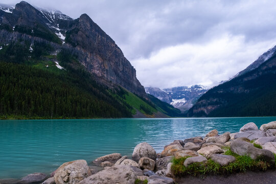 Scenic view of Lake Louise surrounded by mountains and evergreen trees in Banff, Canada during a cloudy day - Powered by Adobe