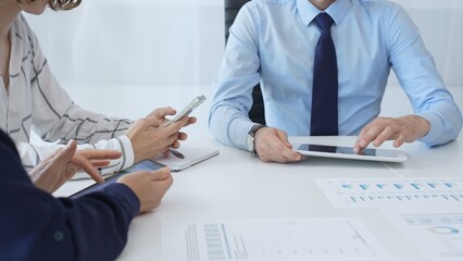 Professional team collaborating, reviewing financial data on digital devices during strategic meeting in contemporary corporate workspace, focusing on performance metrics