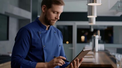 A chef is writing in the restaurant while holding tablet Stock Video - Powered by Adobe